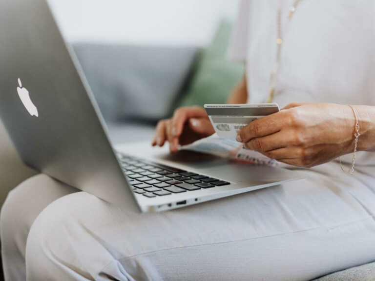 A woman on her laptop doing online mattress shopping, holding her bank card