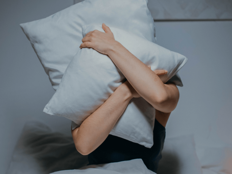 Two pillows getting held together in front of a person's face.